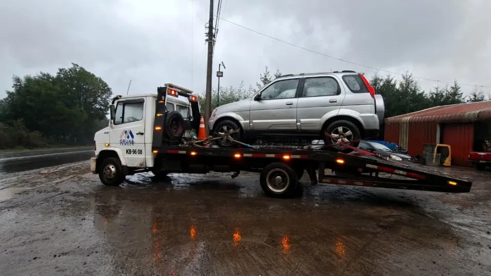 Grúa Mercedes-Benz 912 trasladando un SUV bajo la lluvia